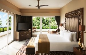 foto grosse suite mit zwei glas wänden und einem grossen doppel bett in der ecke steht ein smart tv fernseher auf einem fernseh tisch mit dschungel und strand und meeres blick im edlen exotischen luxuriösen und hochklassigen disgner hotel resort vivanta b